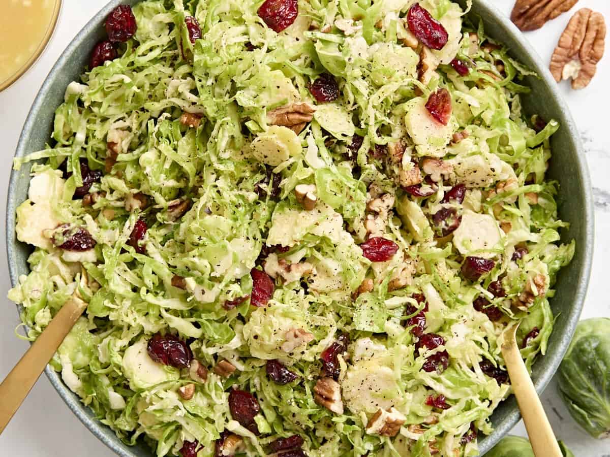 Overhead close up view of a shaved brussels sprouts salad in a serving bowl.