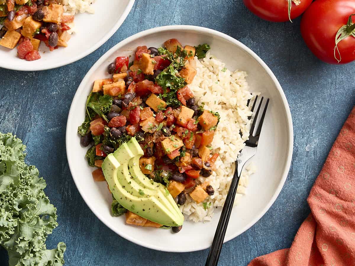 Overhead view of sweet potatoes and black bean skillet with brown rice on a white plate.