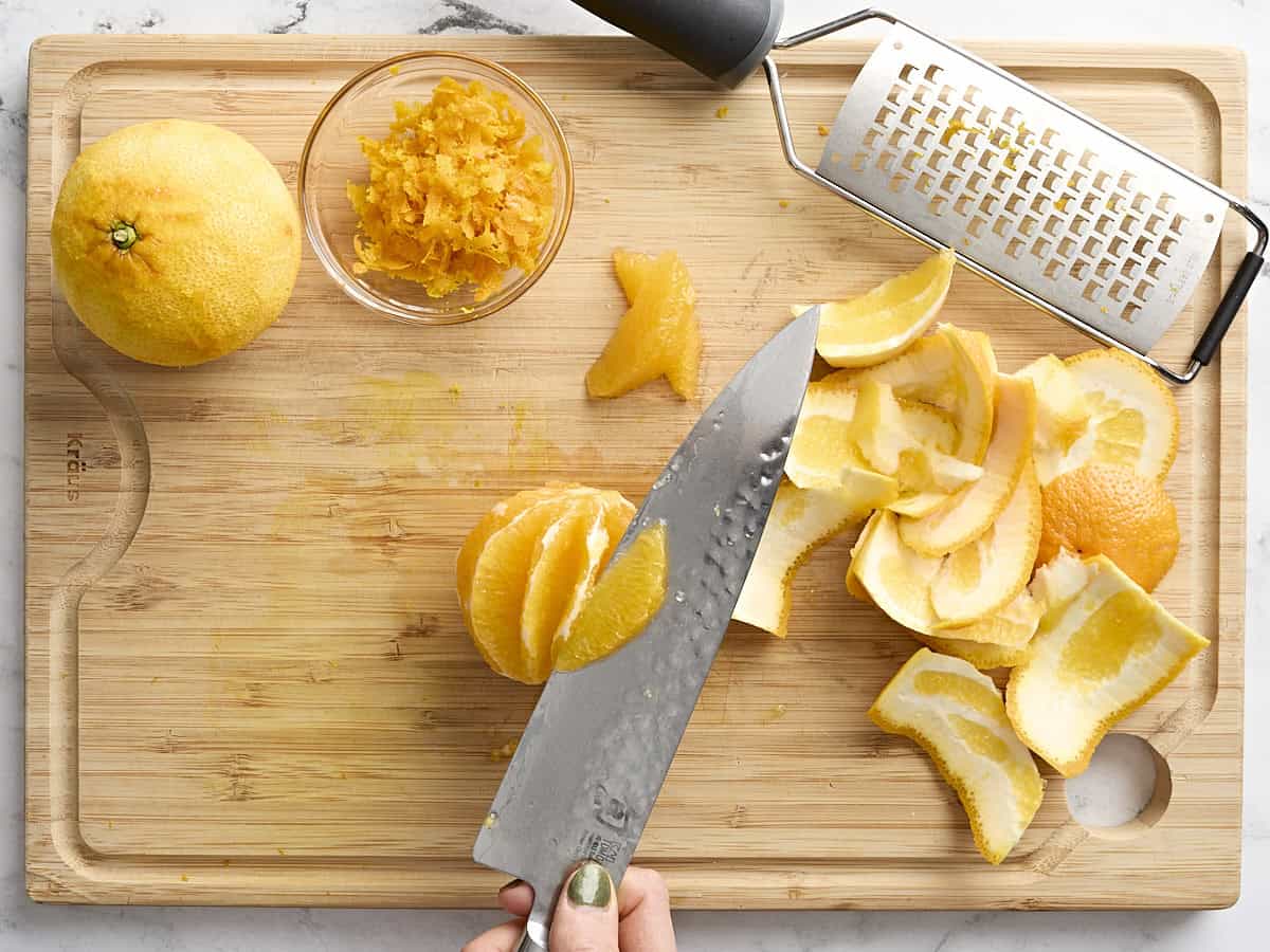 A knife using the supreme cut to slice an orange.