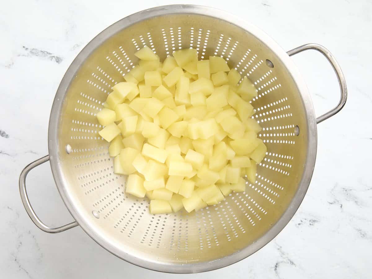 Drained diced potatoes in a strainer.