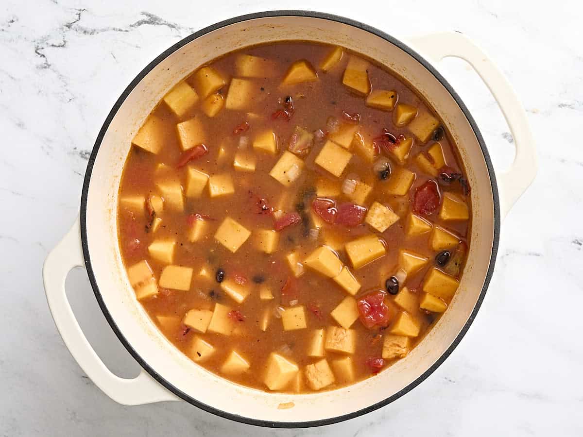 Butternut squash and black bean soup half way through cooking in a dutch oven.