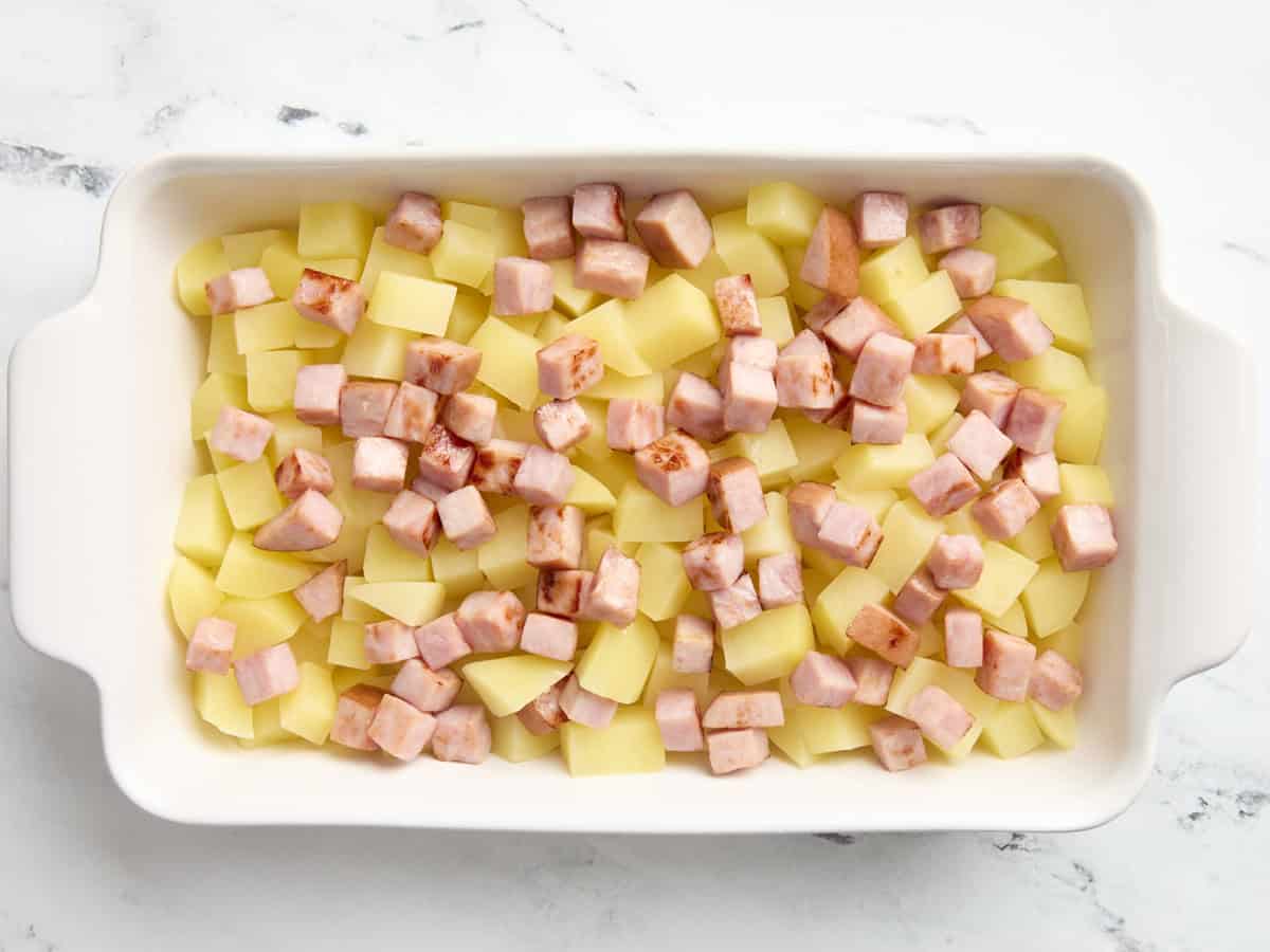 Diced potatoes and ham steak in a casserole dish for ham and potato casserole.