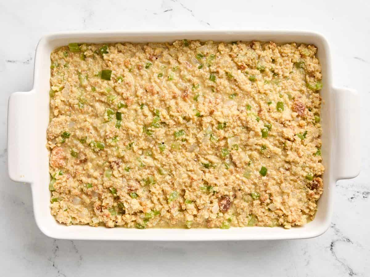 Pre-baked cornbread dressing added to large casserole dish.