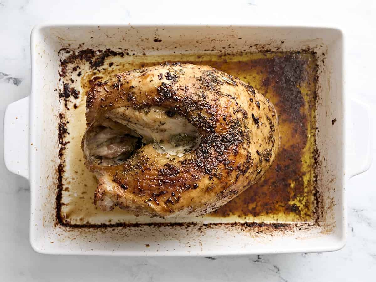 Cooked roasted turkey breast inside baking dish.