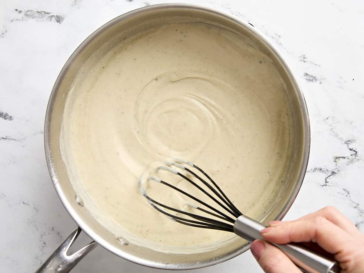 A hand whisking the sauce for turkey pot pie.