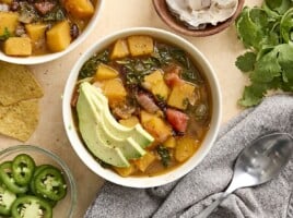 Overhead view of a bowl of butternut squash with black beans soup, topped with avocado.