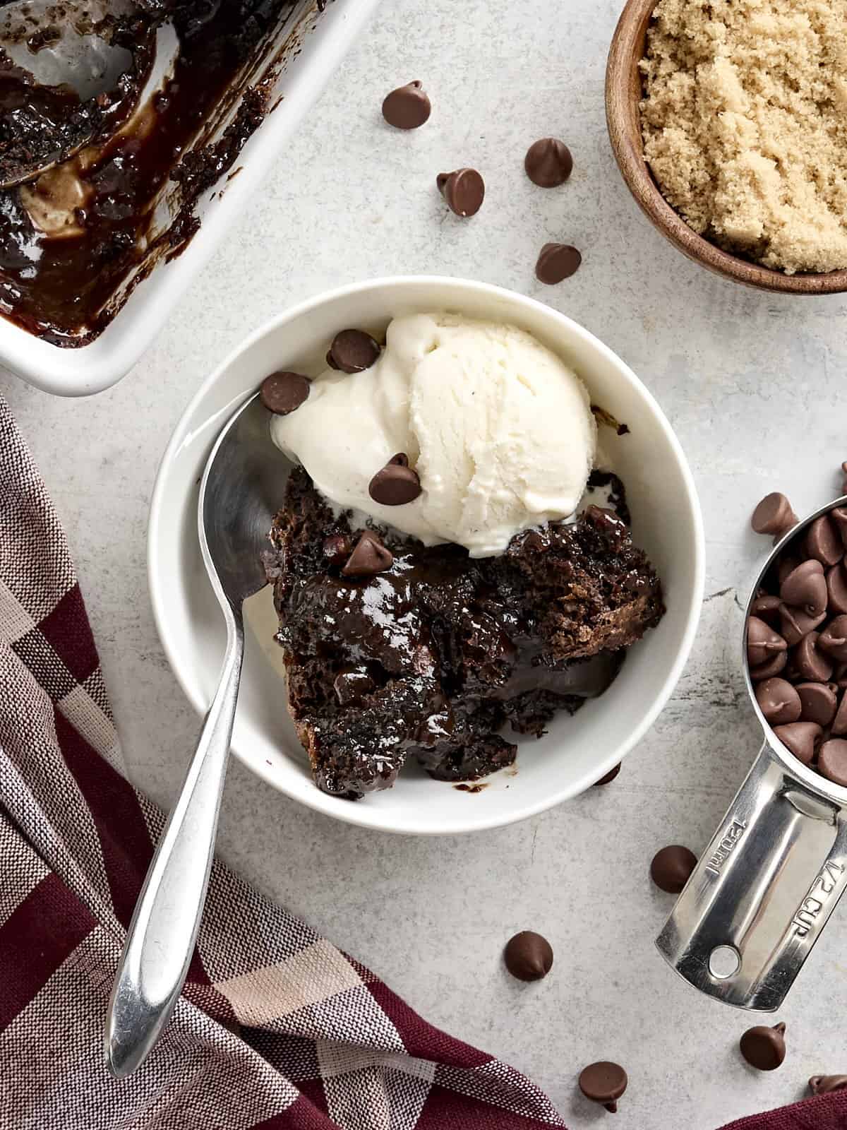 Overhead view of a slice of chocolate pudding cake in a bowl with vanilla ice cream.