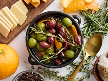 Overhead view of a bowl of marinated olives with fresh herbs.