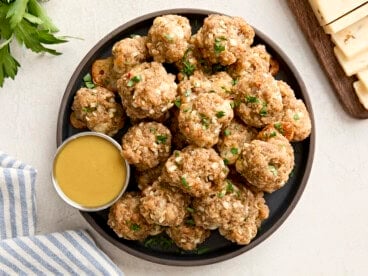 Overhead view of sausage balls on a plate with a side of honey mustard sauce.