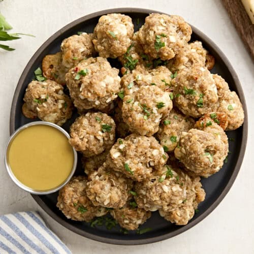 Overhead view of sausage balls on a plate with a side of honey mustard sauce.