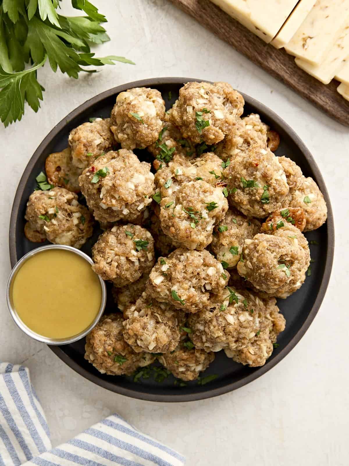 Overhead view of sausage balls on a plate with a side of honey mustard sauce.