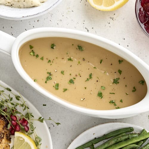 Overhead view of turkey gravy in a gravy boat sprinkled with fresh parsley.