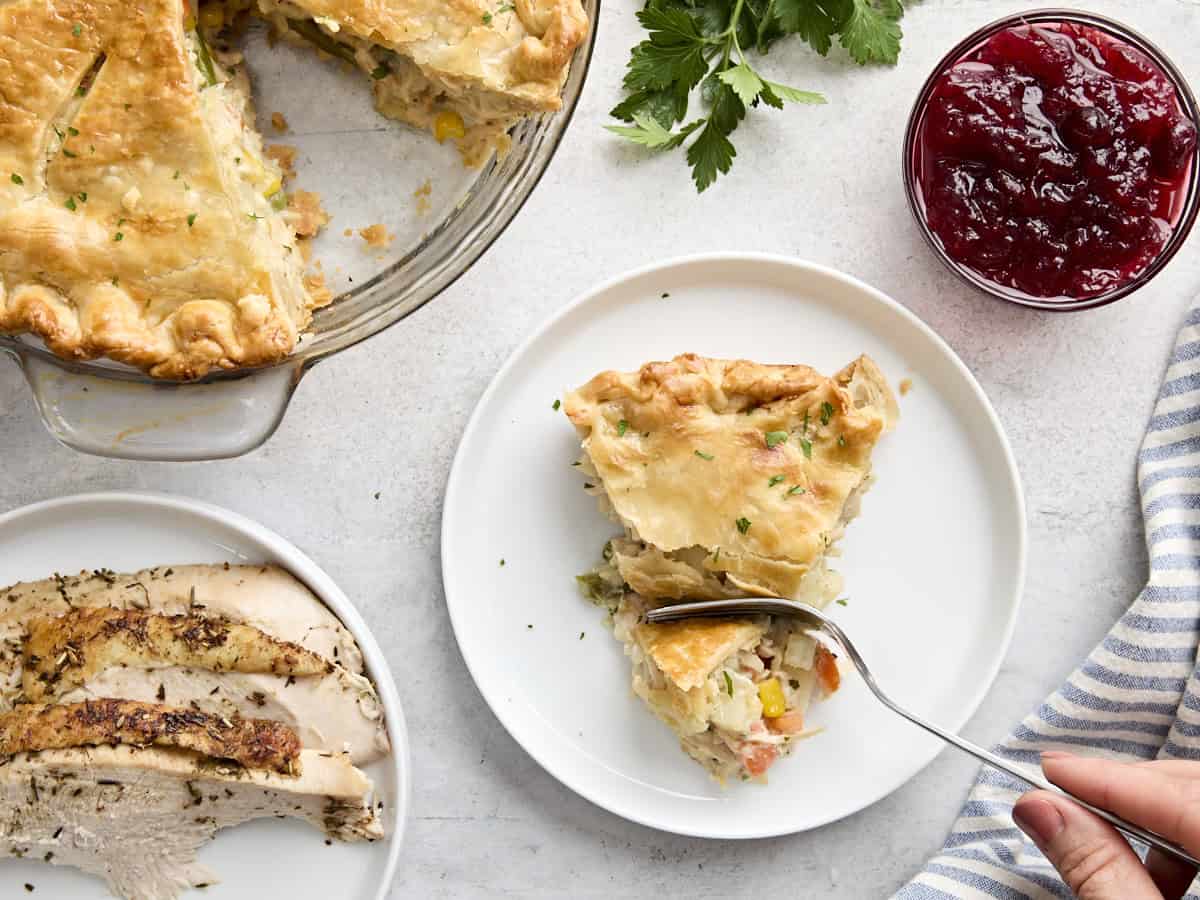 Overhead view of a  fork digging into a slice of turkey pot pie on a plate.