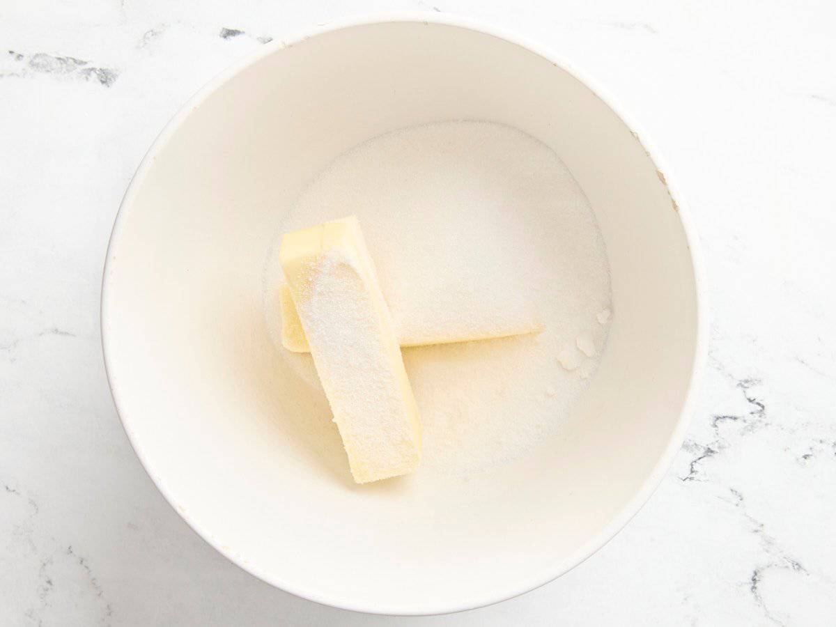 Two sticks of butter and sugar in a bowl.