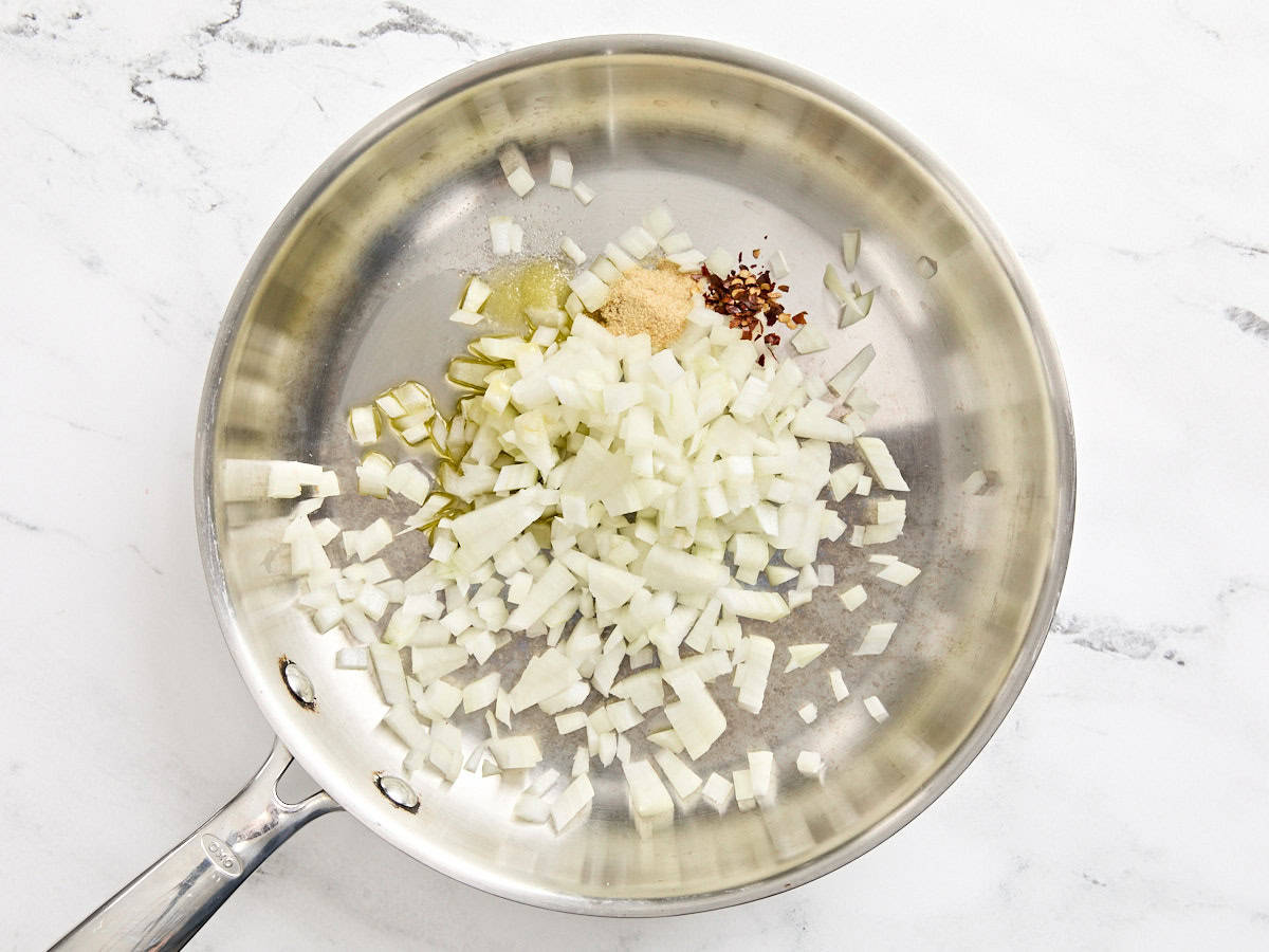 Diced onions with seasoning in a skillet.