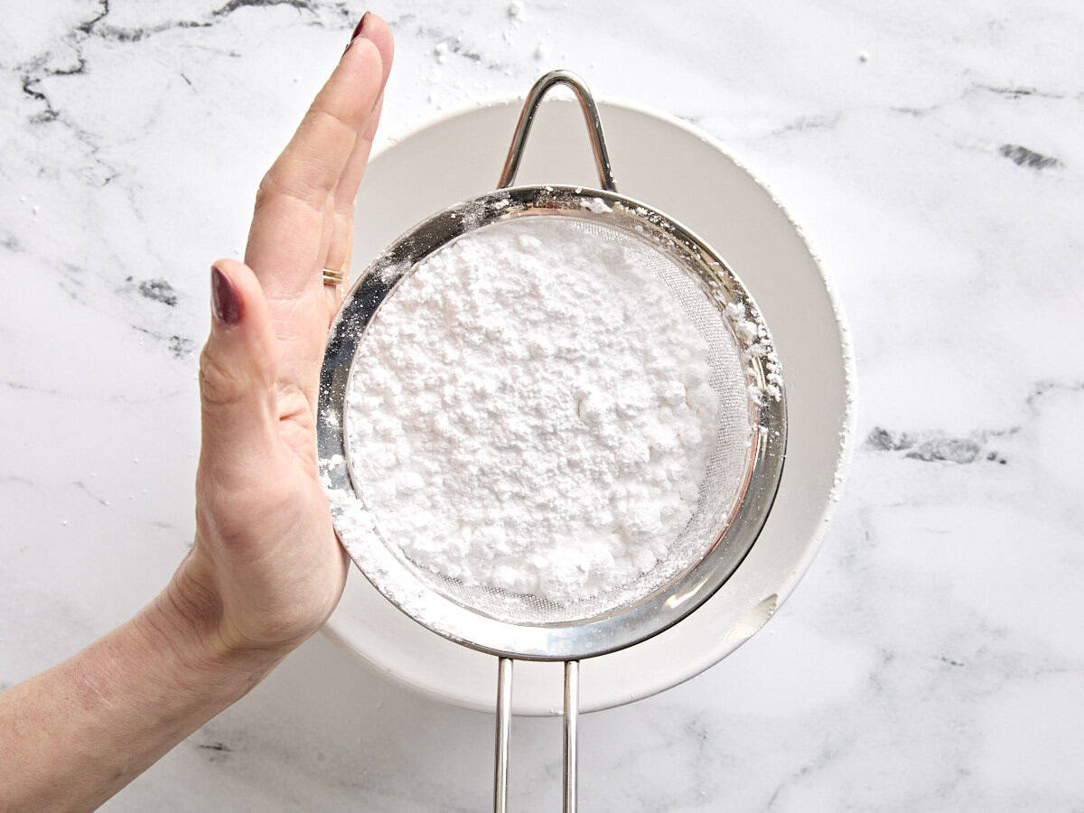 Powdered sugar being sifted into a bowl.