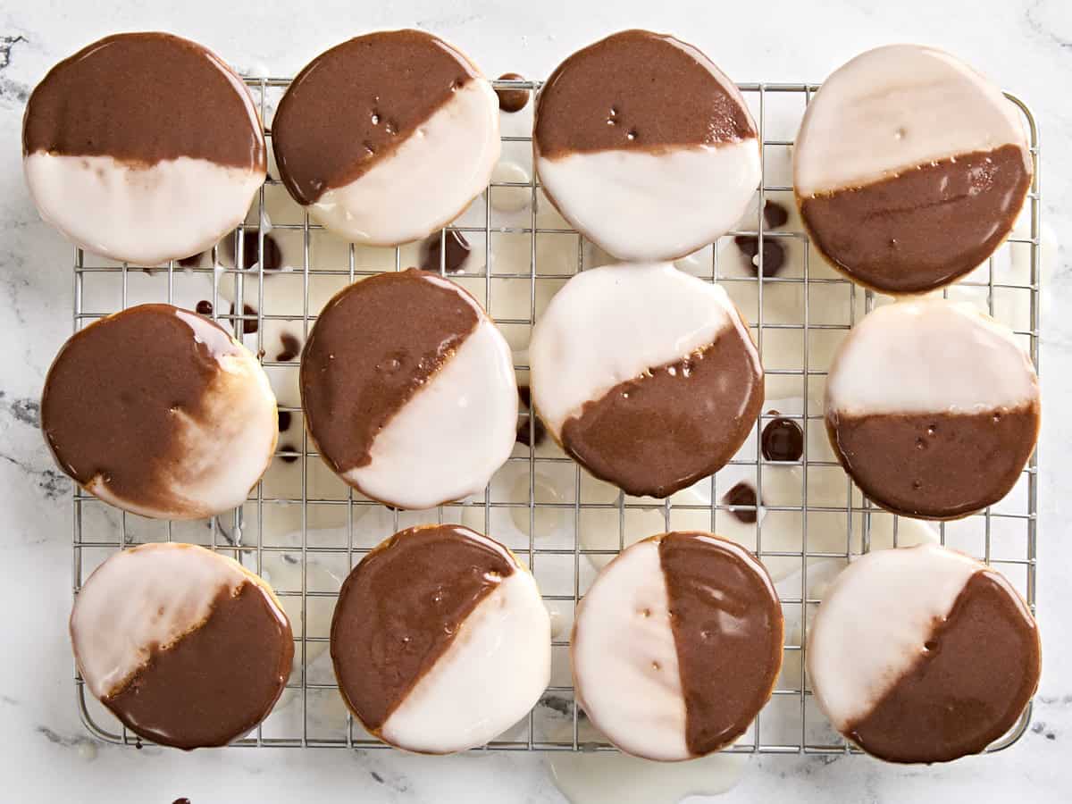 Finished black and white cookies on a wire rack.