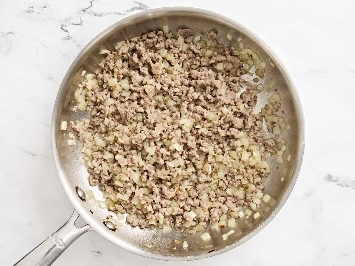 Ground sausage and onion cooking in a skillet.