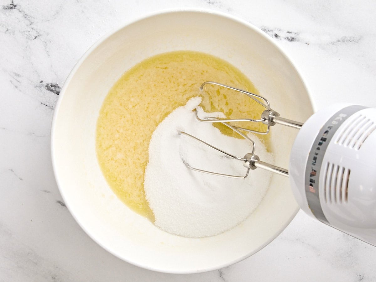 Melted butter and sugar being whisked in a bowl.