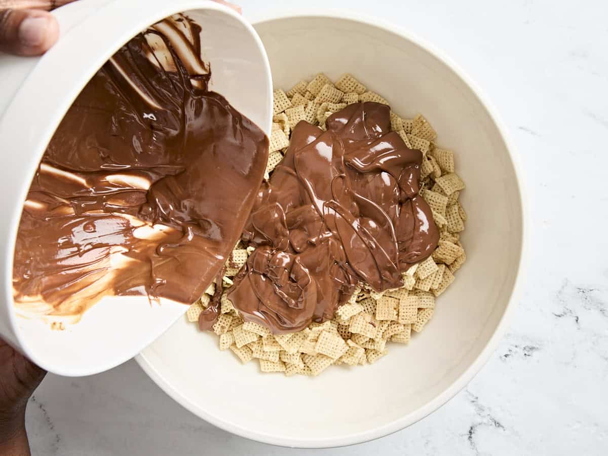 Melted chocolate and peanut butter being added to a bowl of rice chex cereal.