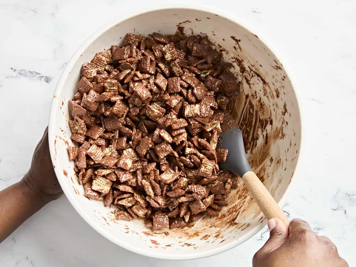 A spatula mixing together melted chocolate and rice chex cereal.