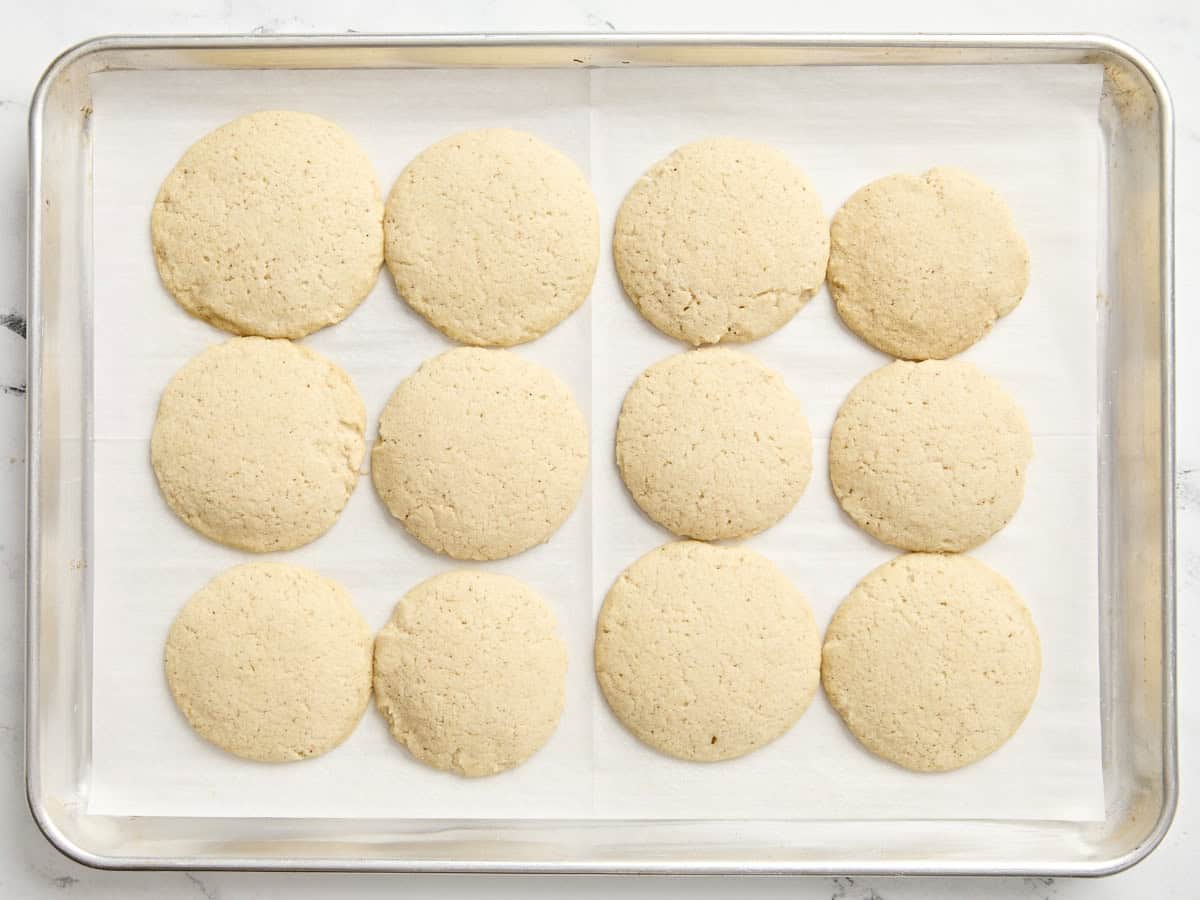 Baked eggnog cookies on a parchment lined baking sheet.