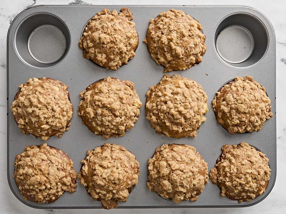 Freshly baked apple and cinnamon muffins in a muffin pan.