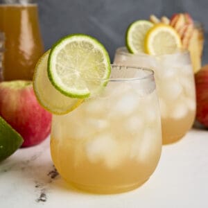 Side view of Apple Cider Shrub Mocktail with lemon and lime for garnish.