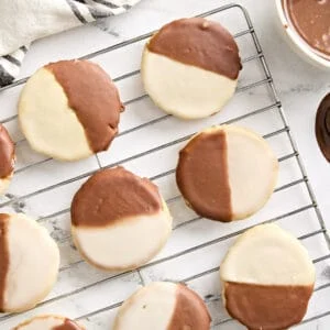 Overhead view of black and white cookies on a wire rack.