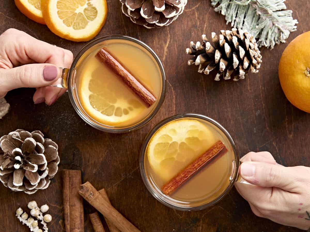 Overhead view of two hands holding a mug of hot apple cider.