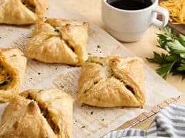 Side view of sausage and cheese hand pies on parchment paper.