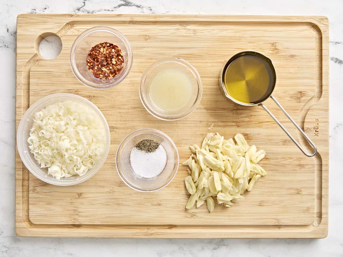 The ingredients for Spaghetti Algio e Olio on a wooden cutting board.