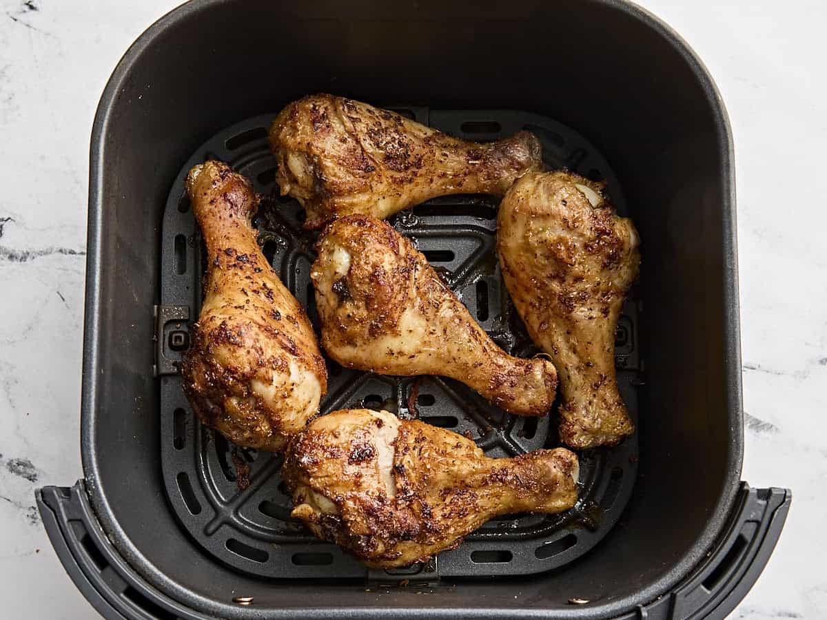 Air fried chicken drumsticks in an air fryer basket.