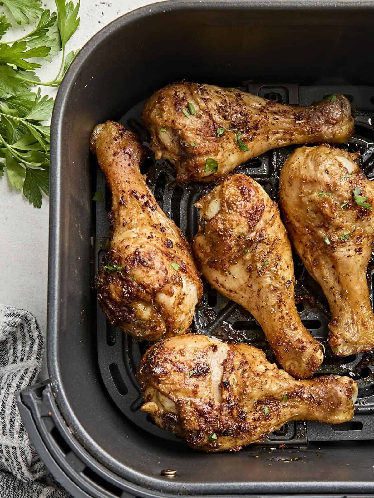 Overhead view of air fried chicken drumsticks in an air fryer basket.